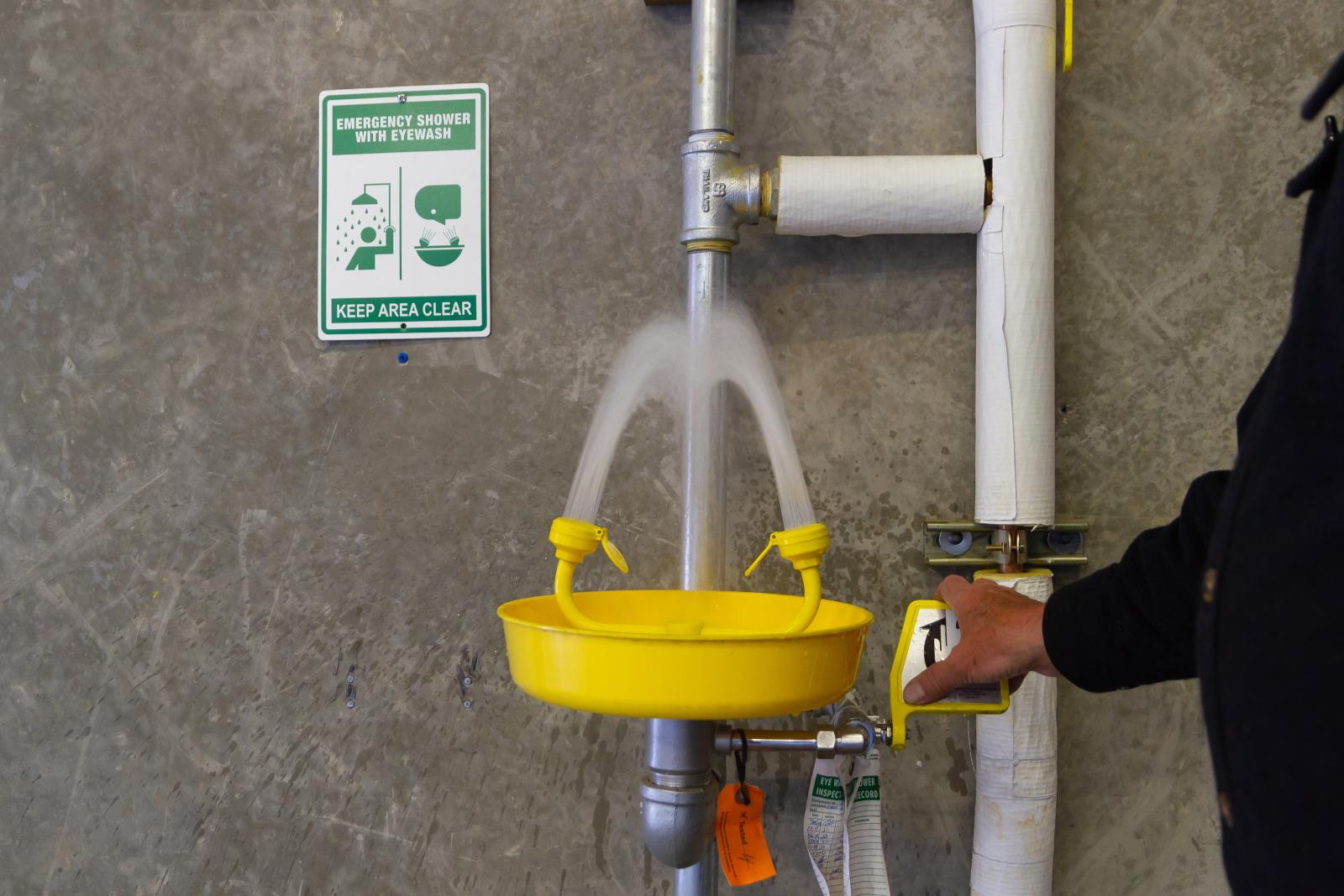 Photo of an individual turning on an eyewash station.
