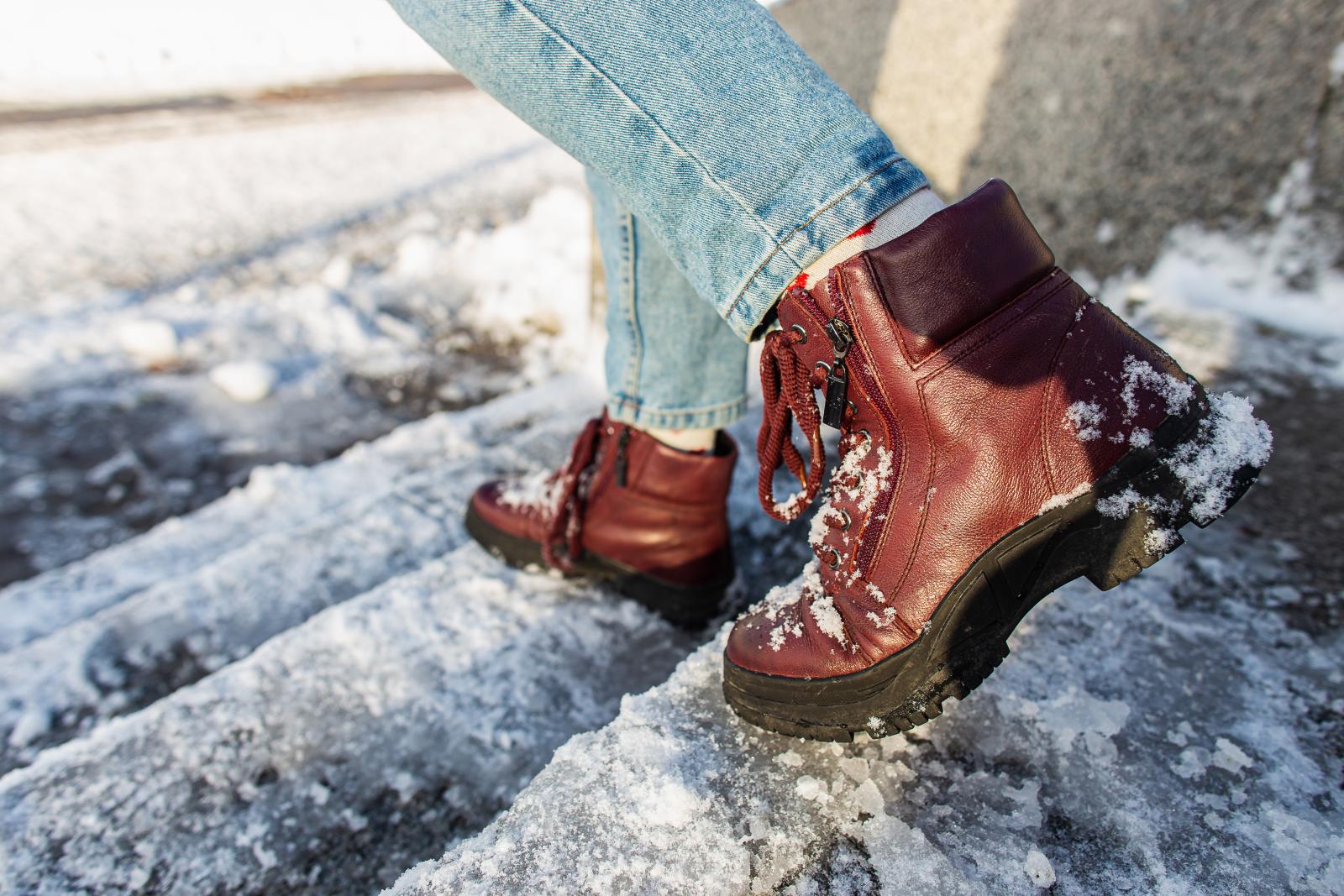 Image of an individual walking down stairs covered in ice while wearing brown boots.